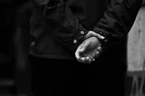 sort/hvid foto af en anholdt mand med hænderne bag ryggen